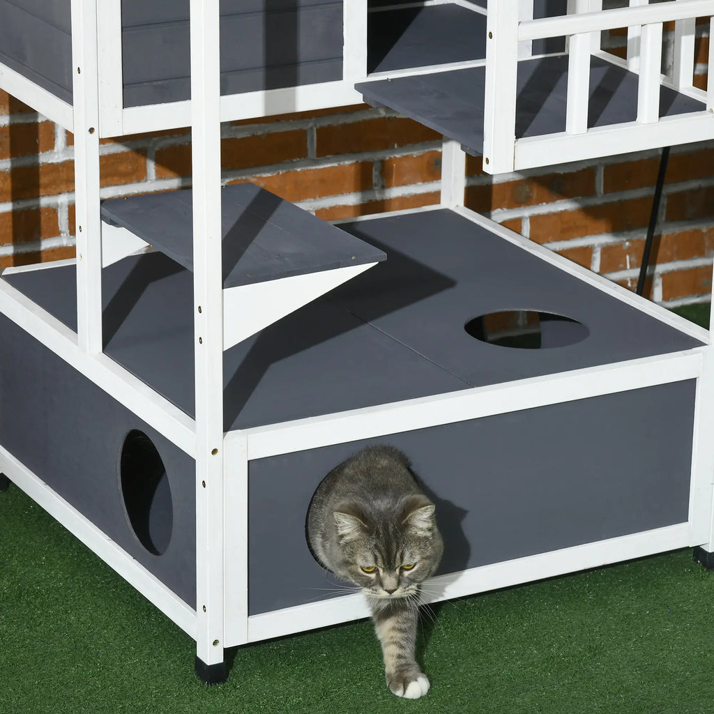 Cat playing on a multi-level cat tree with gray platforms and white frame.