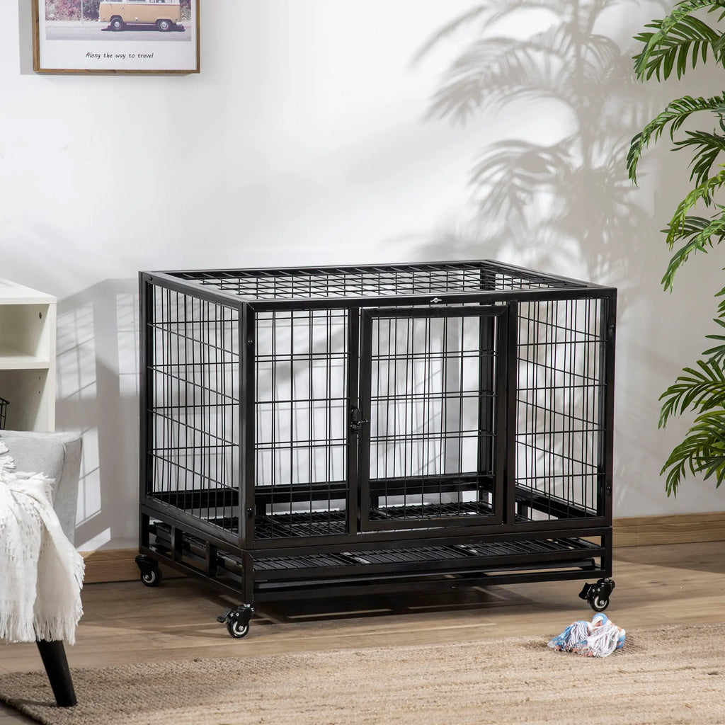 Large black metal dog crate in a room with a white wall and plant.