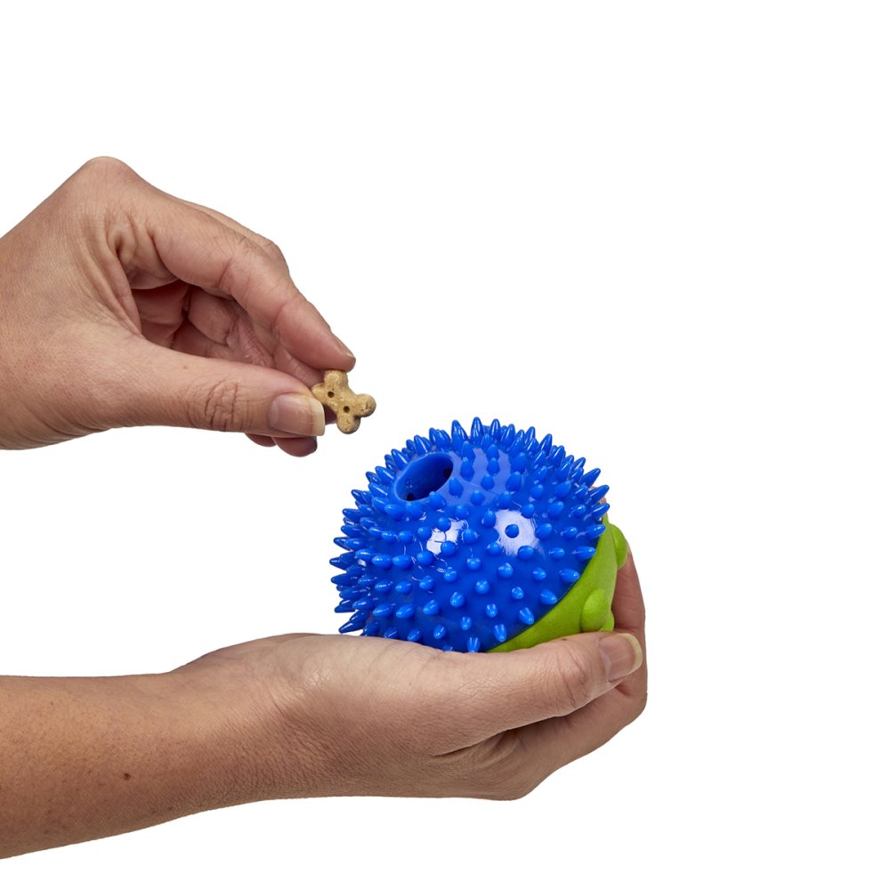 Blue and green spiky ball with a small puzzle piece held by a hand on a white background