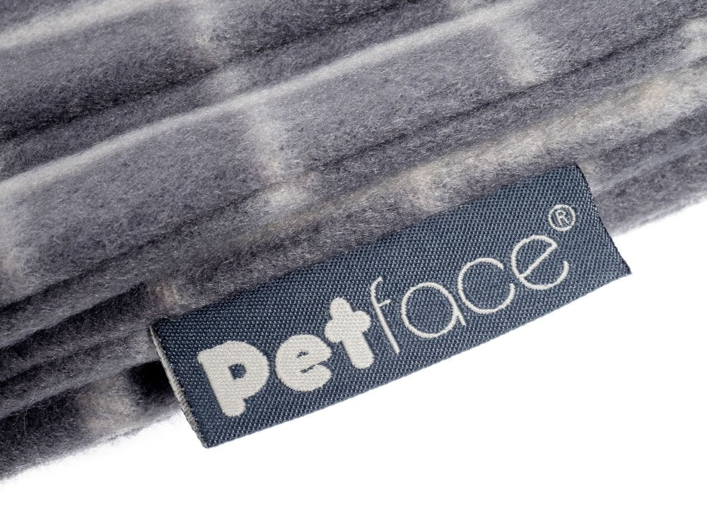 Close-up of a 'Petface' label on a textured gray fabric background