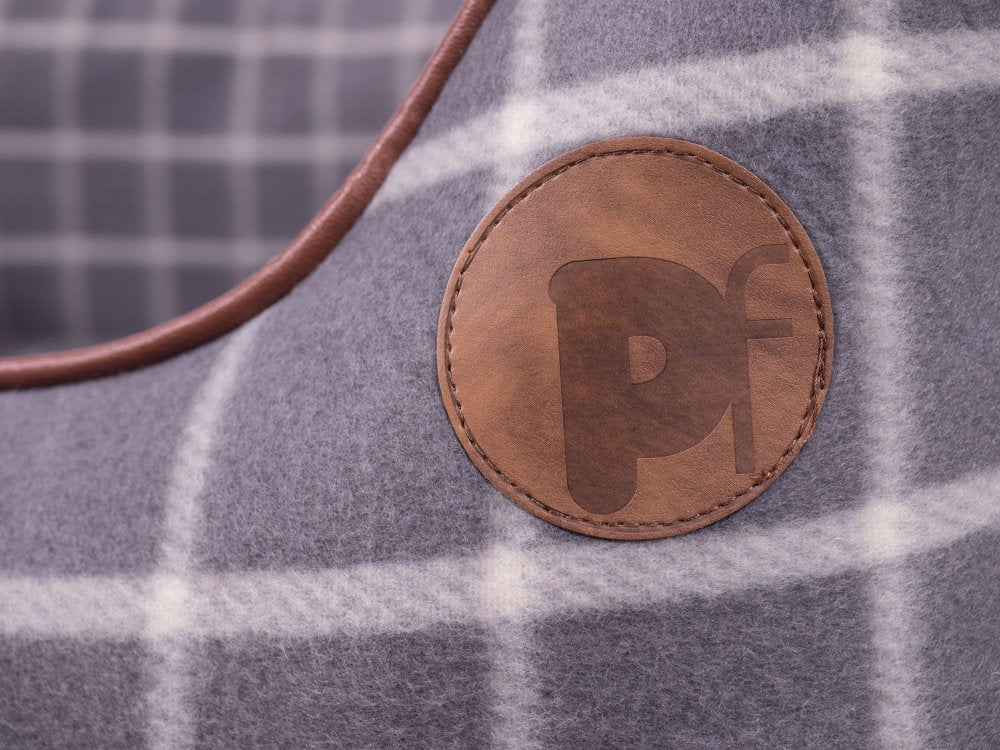 Close-up of a brown leather patch with 'PF' logo on a plaid fabric background