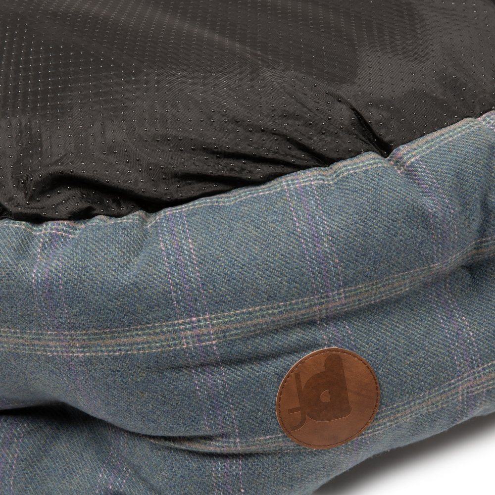 Close-up of a dog bed with a brown leather patch. 