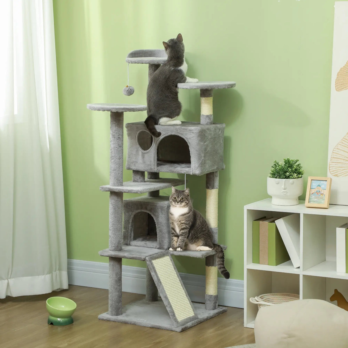 Grey indoor cat tower with platforms, scratching areas and a cat playing in a home setting