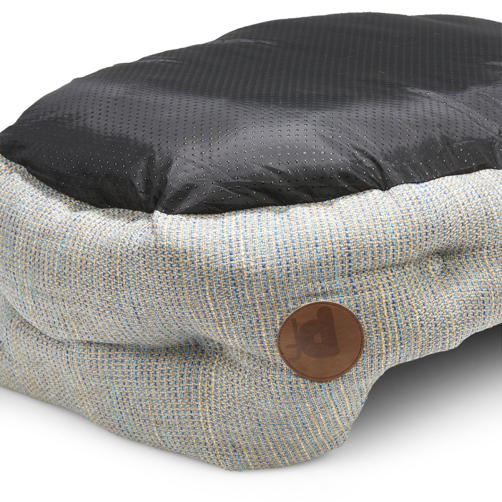 Dog bed with black cushion and woven fabric on a white background