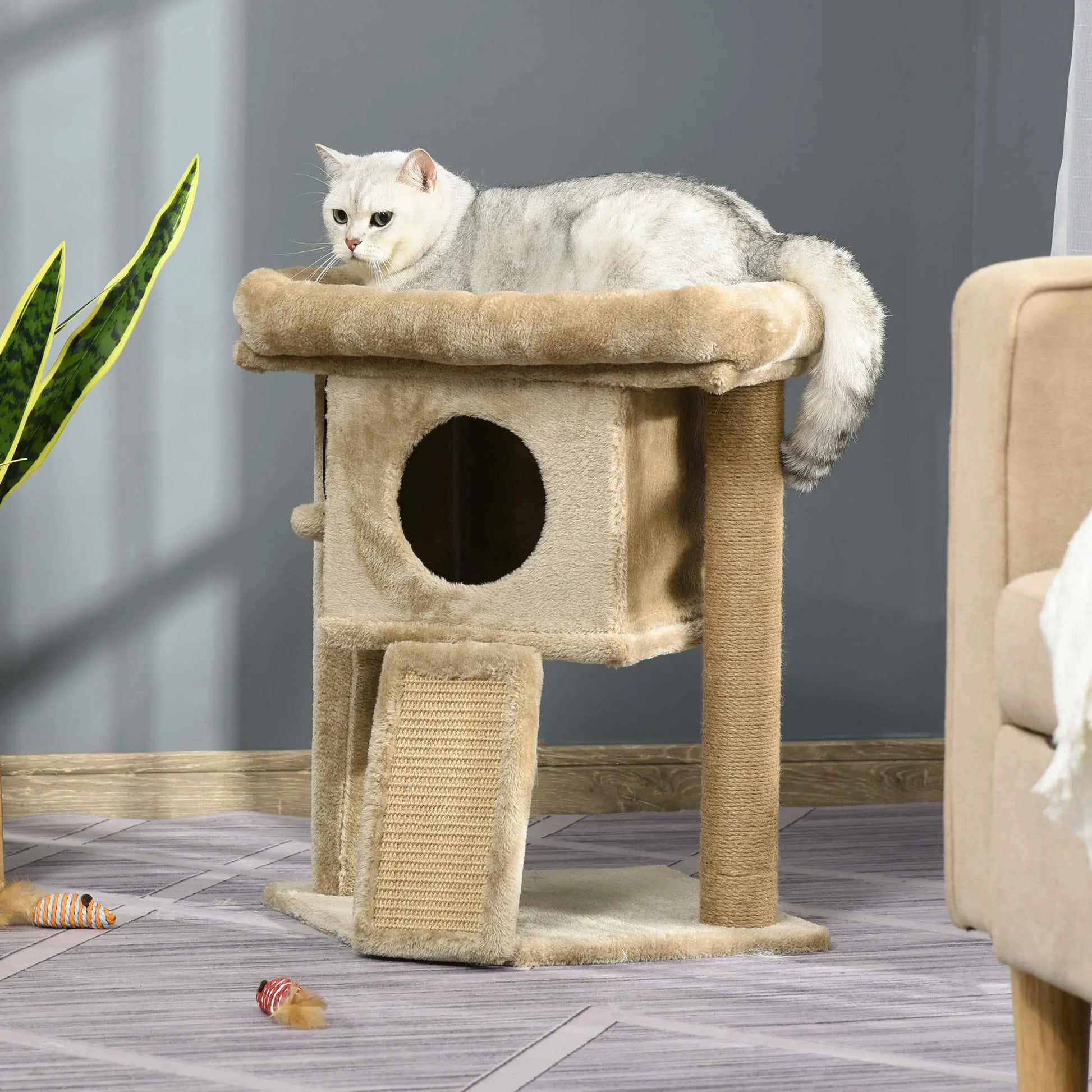 Cat sitting on a beige cat tree in a room with a plant and furniture.