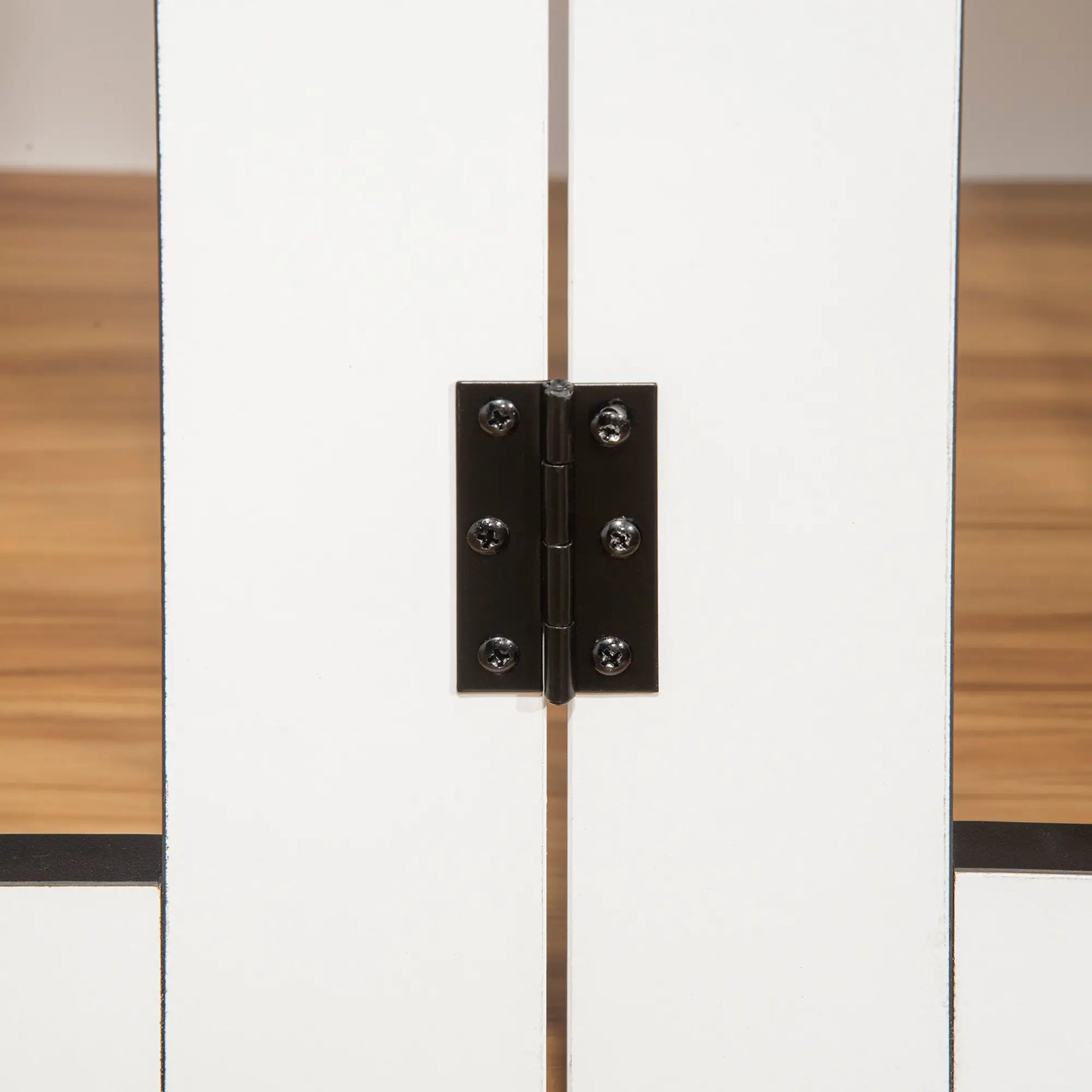 Close-up of a black metal hinge on a white door with wooden panels.